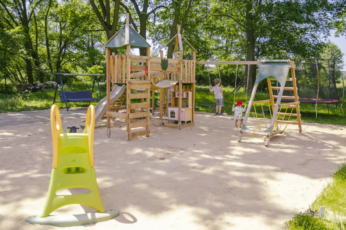 Großer Spielplatz zwischen Bäumen auf dem Pausenhof