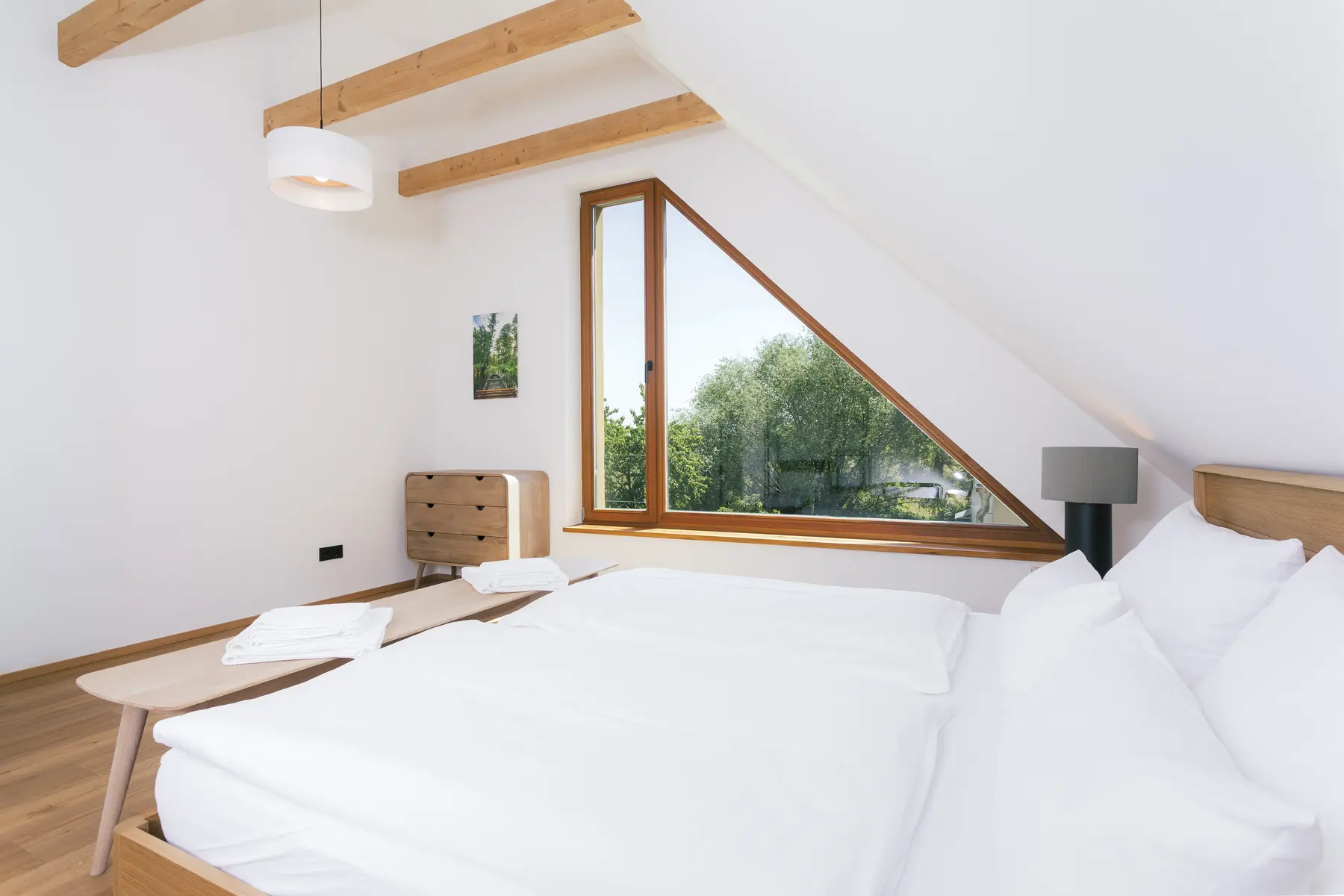 Helles Schlafzimmer der Wohnung Spreeblick mit großem Doppelbett und Blick ins Grüne